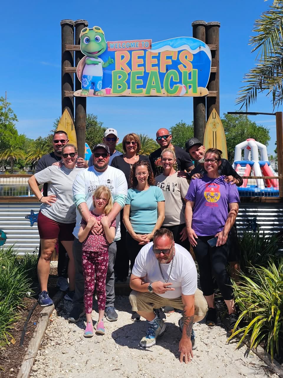 Multigenerational family group in front of beach sign