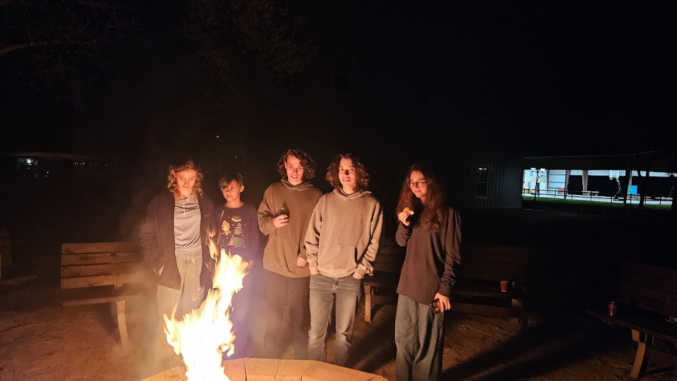 Teens sitting around a warm campfire at night